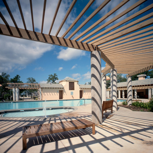 A large community pool and its surround amenities, furniture, and shading structure.
