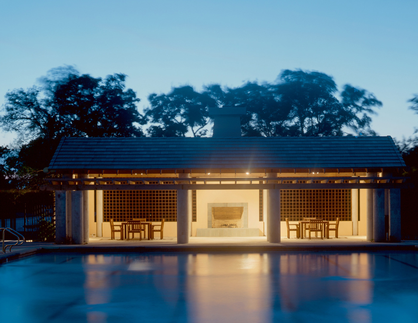 A patio fireplace structure beside a large community pool.