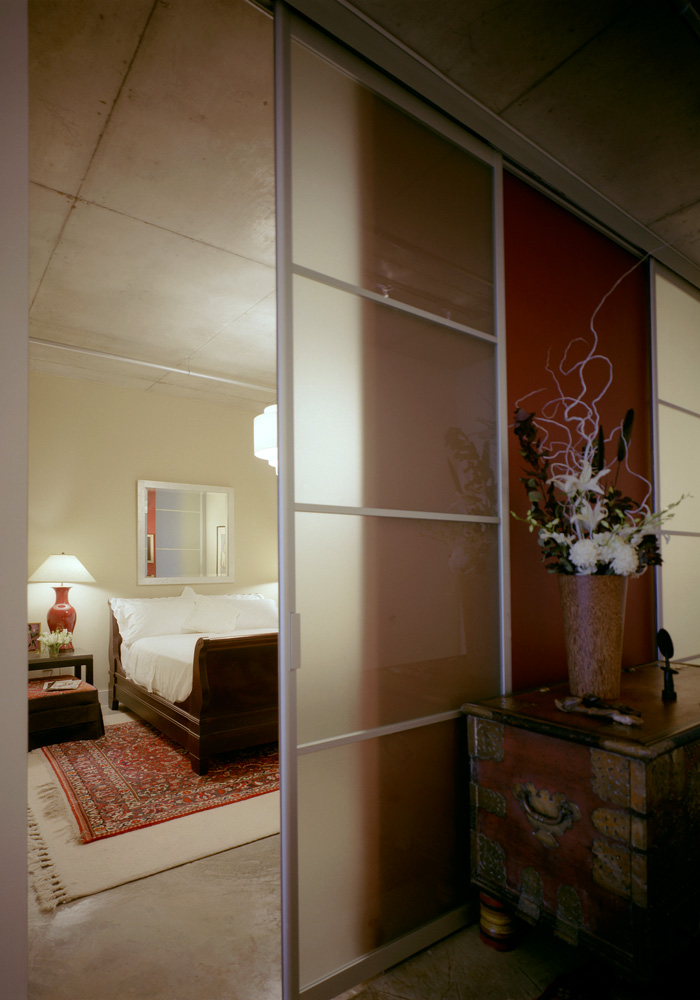 A bed visible through a sliding screen door.