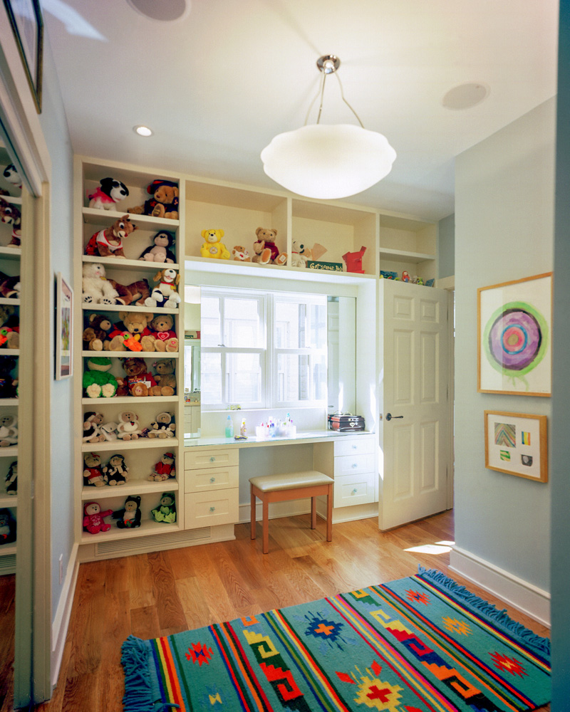 A child's desk and shelf built into a windowed wall.