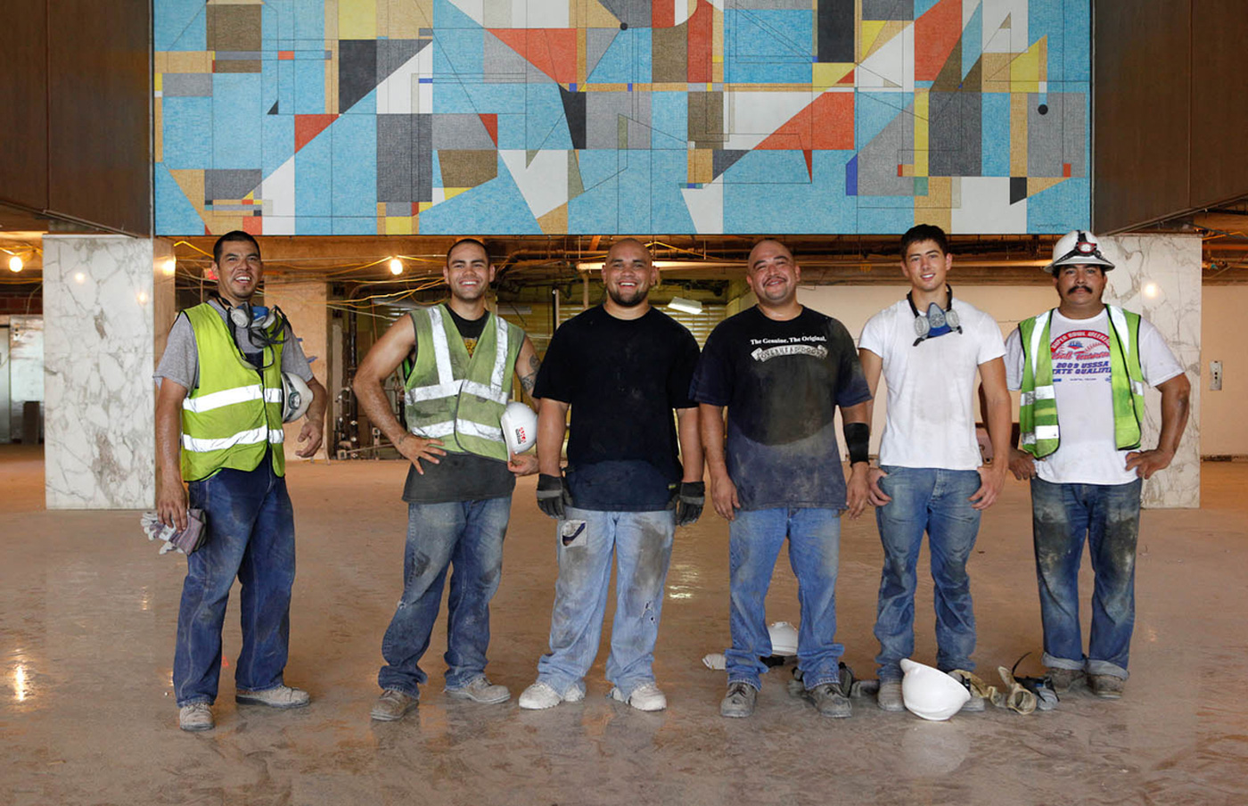 Six constructions workers standing pound in the office space they are renovating.