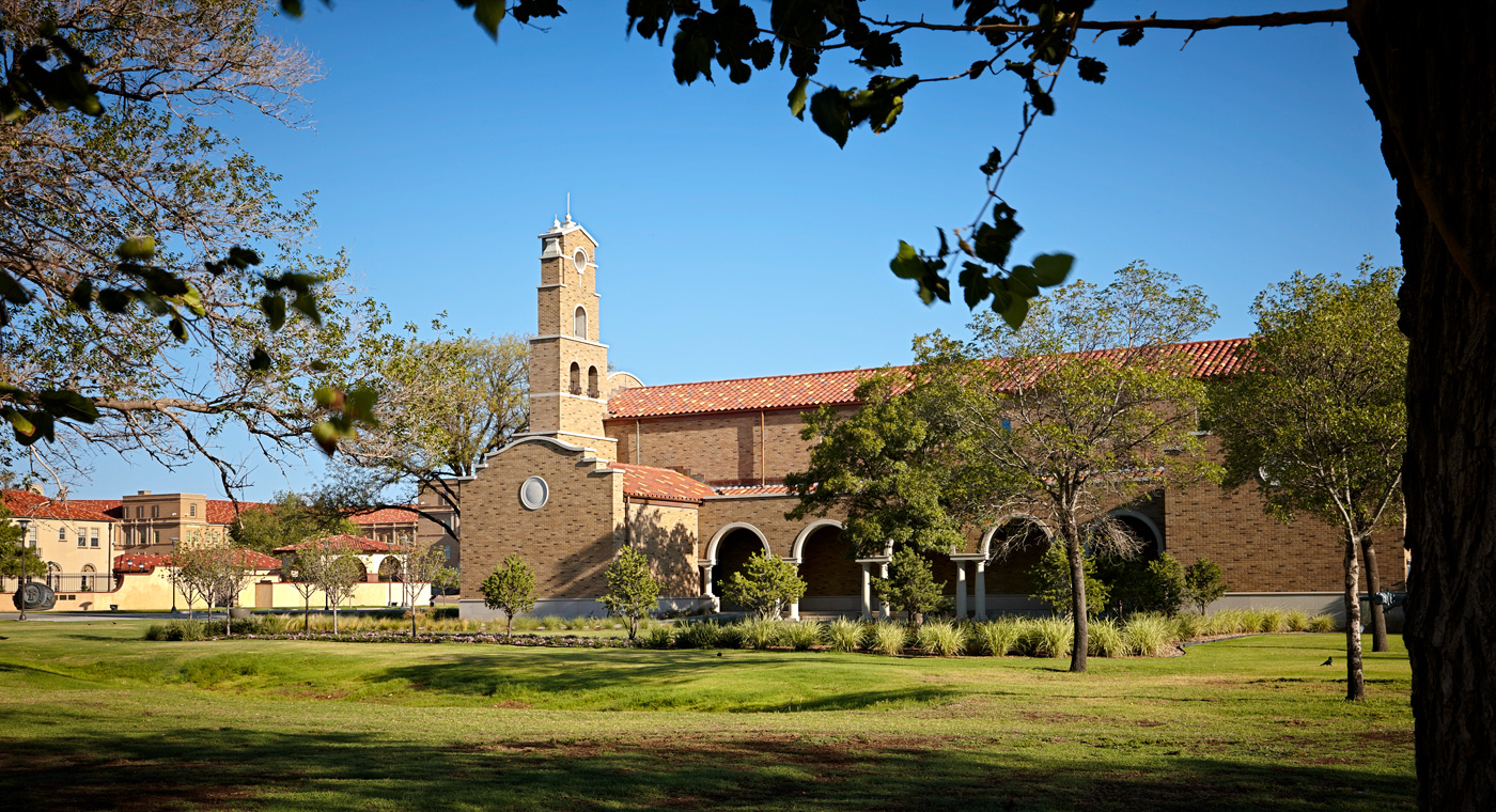 A brick chapel visible from its connected lawn and landscaping.