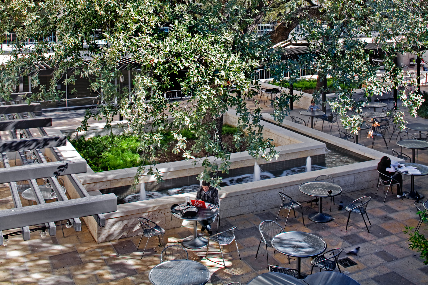 Student working at patio table around a fountain feature.