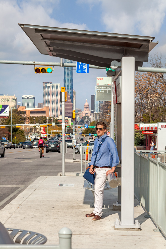 Businessman waits patiently for bus on a sunny day.