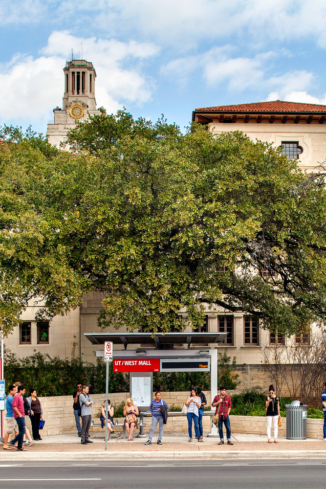 University of Texas students waiting for bus at bus stop along the drag.