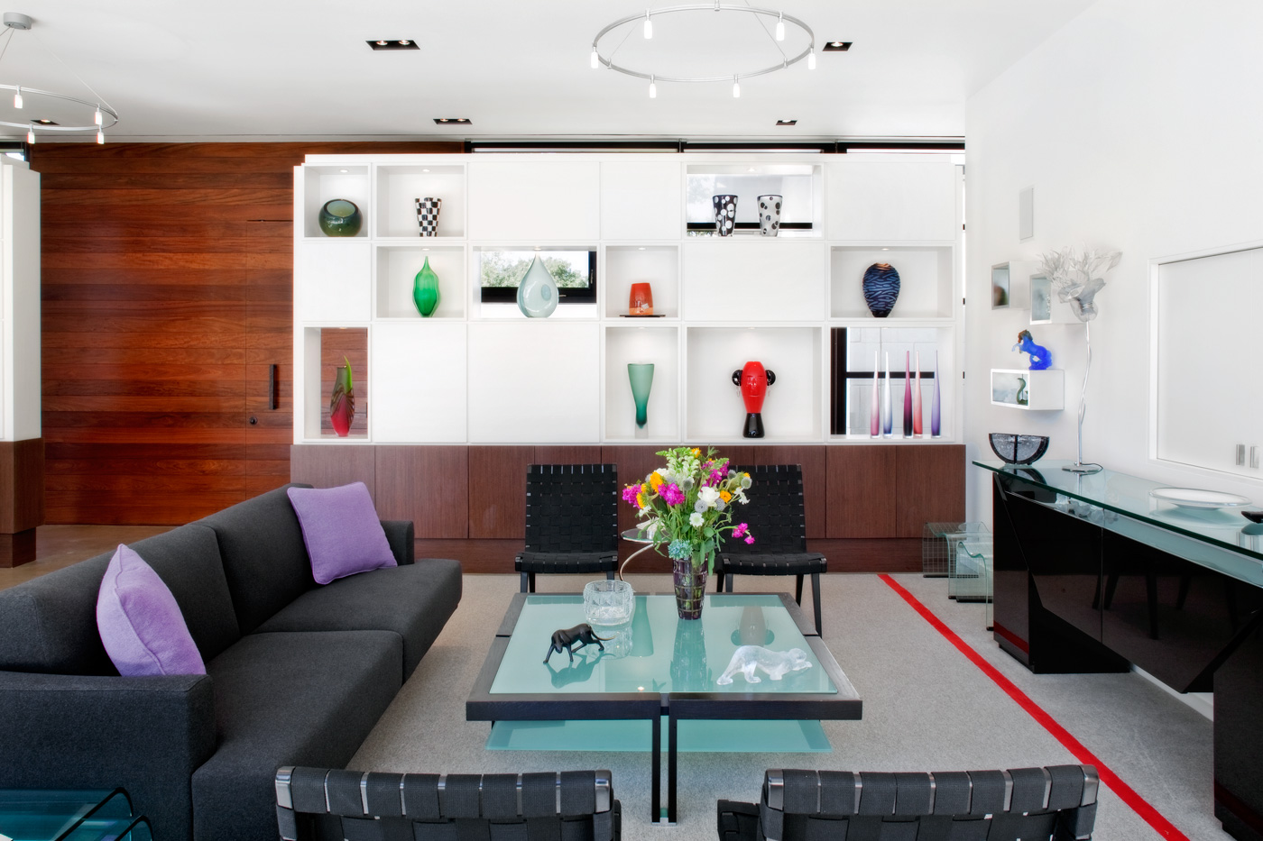 A living room with built in shelf system and black furniture.