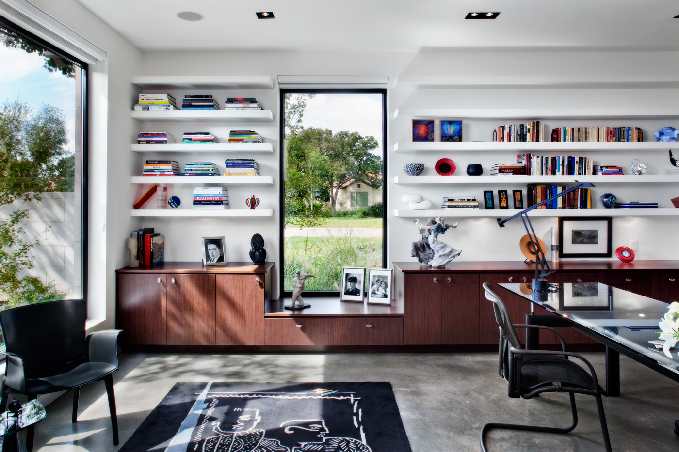 A homes office with long built in shelves lining the walls.