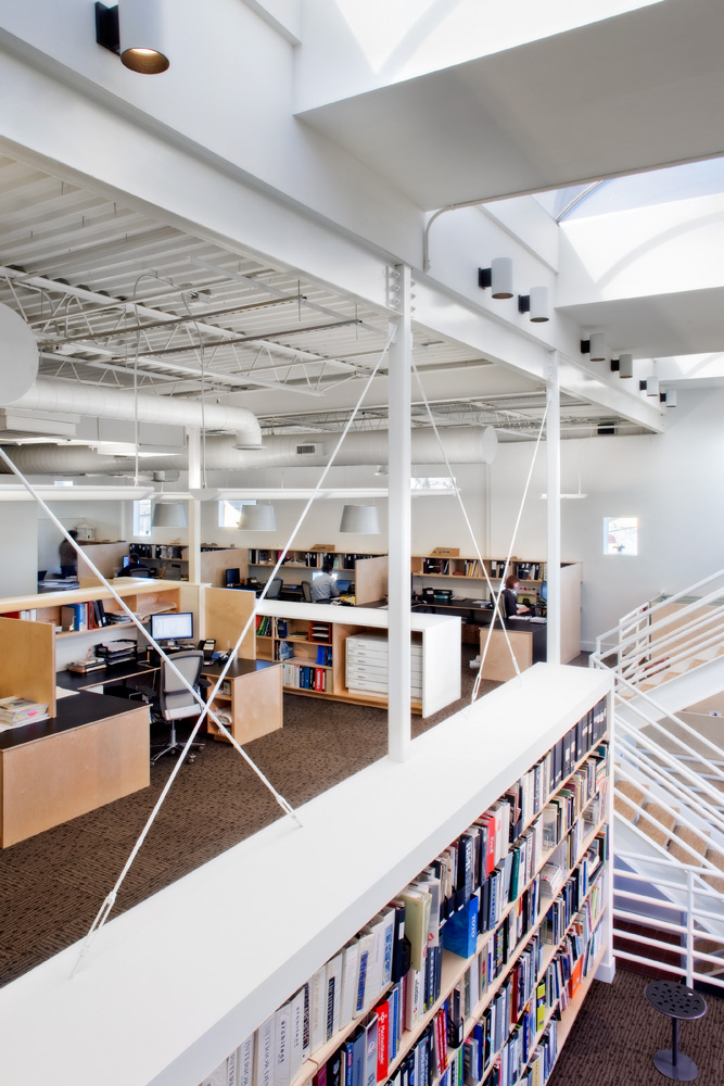 A two-floor office space with cubicles and a large bookshelf.