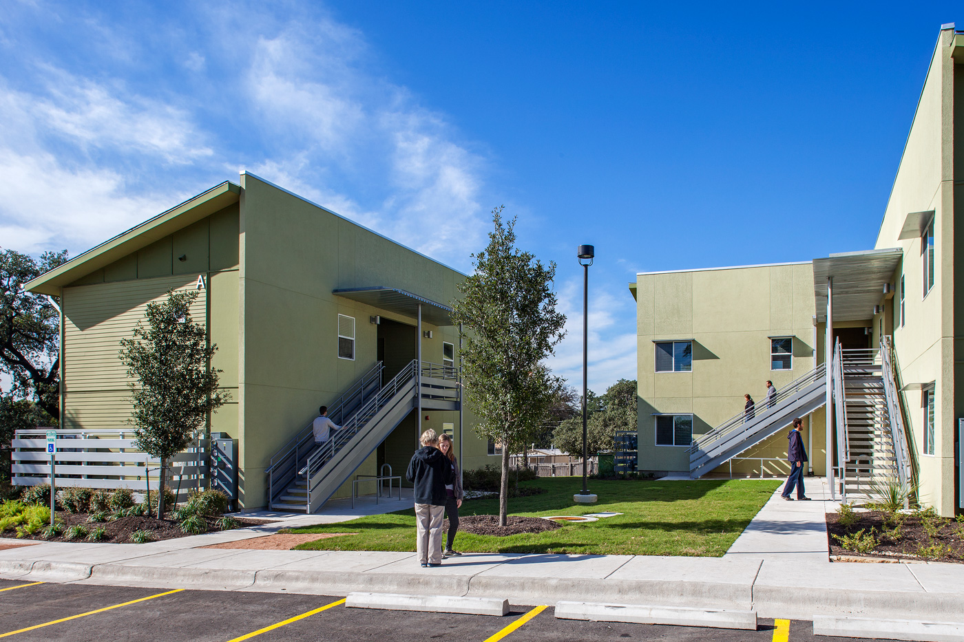 People walking in and out of apartments that share an interior courtyard.