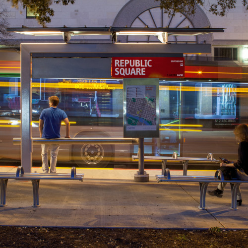 People waiting for bus to arrive at their stop at dusk.