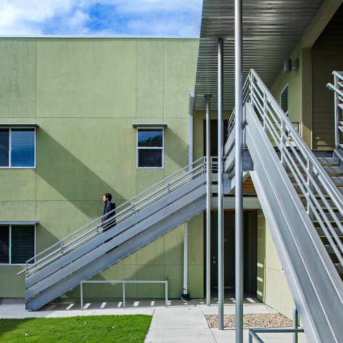 Metal exterior stairs of a green two floor apartment building.