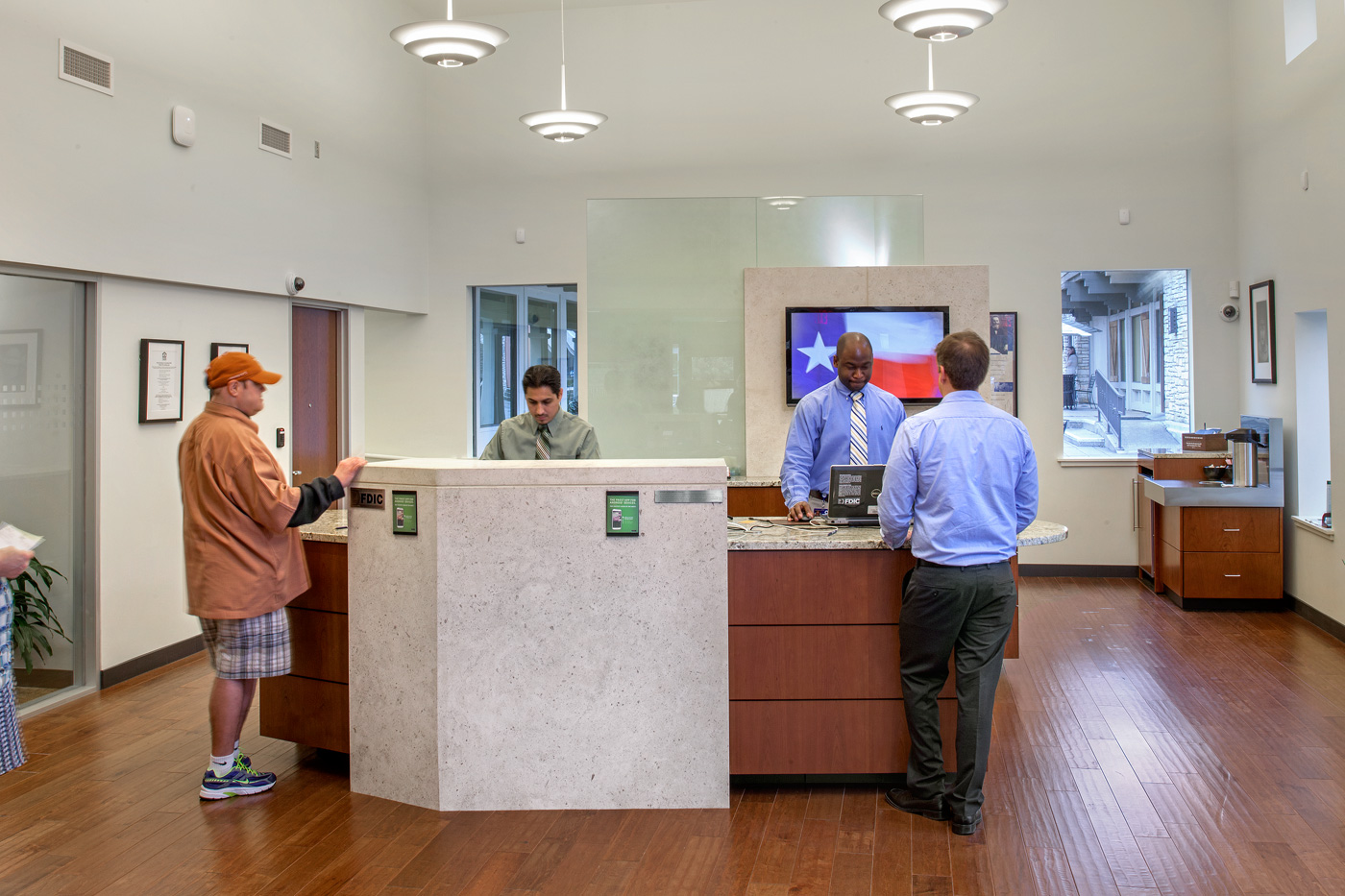 People being assisted at service desk of a frost bank.