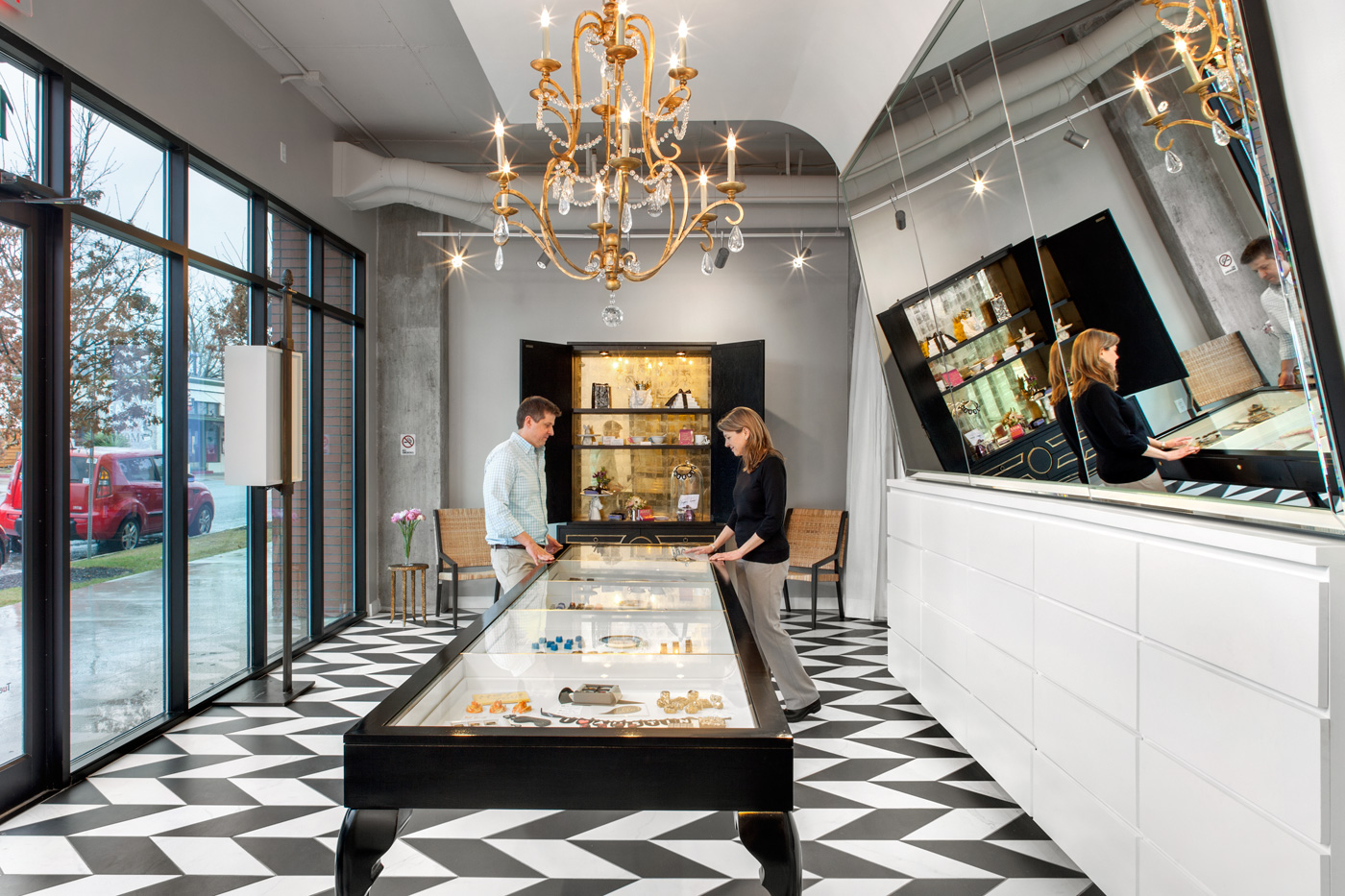 People looking into confections display case in a stores front showroom.