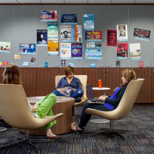 Students working in lounge chairs of a lobby space around a coffee table.