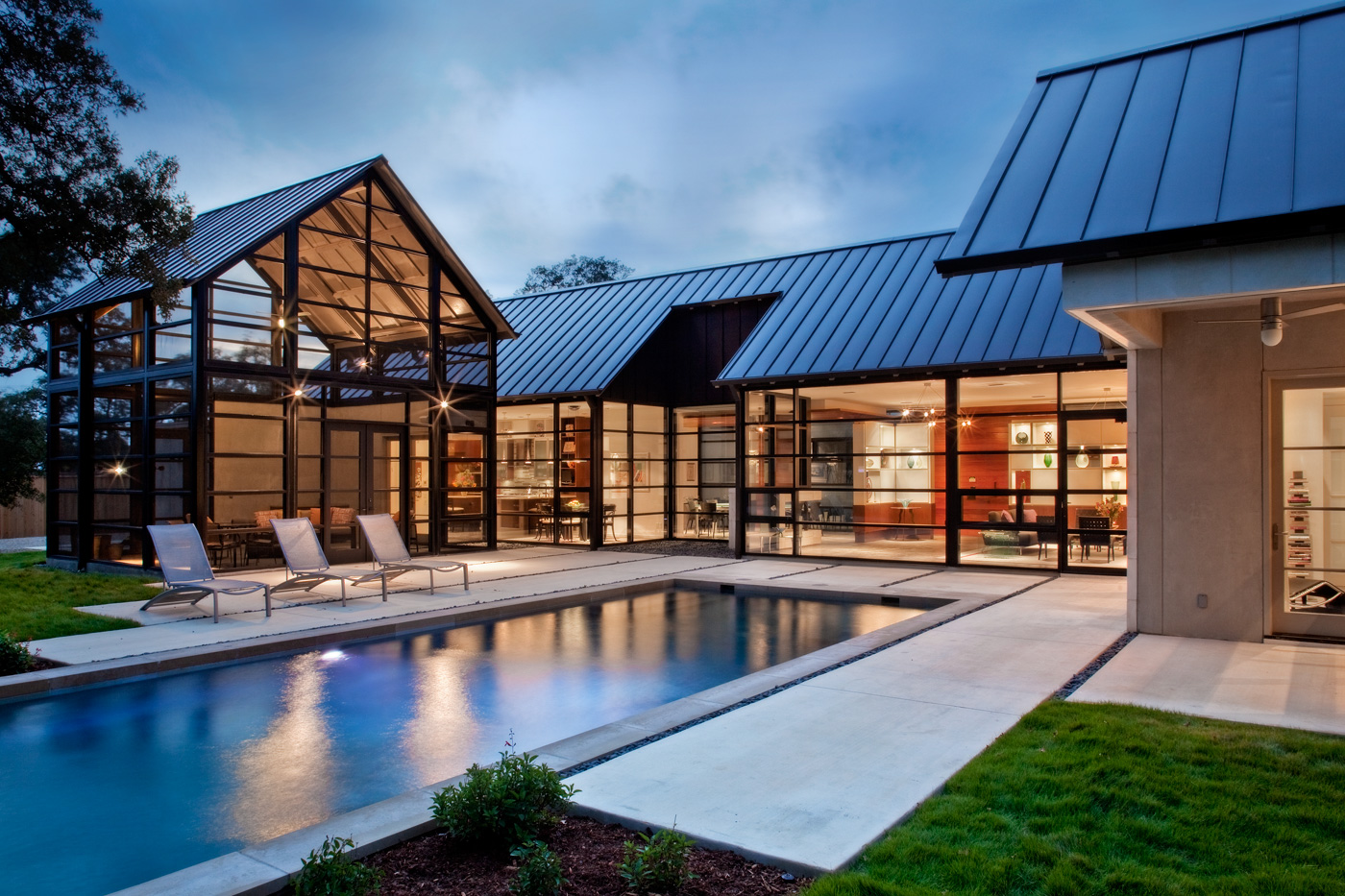 A homes backyard patio area and pool with view into homes dining and living rooms.