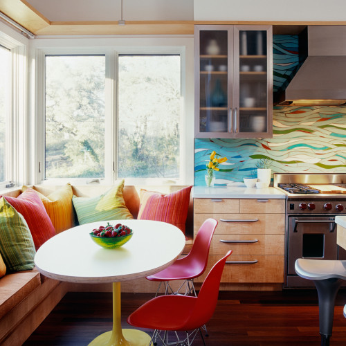 A small dining corner connected to kitchen with colorful. backsplash.