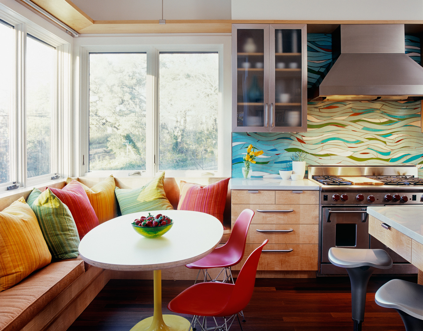 A small dining corner connected to kitchen with colorful. backsplash.