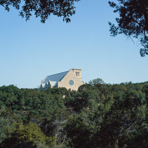 The top of a church raising through trees in the distance.