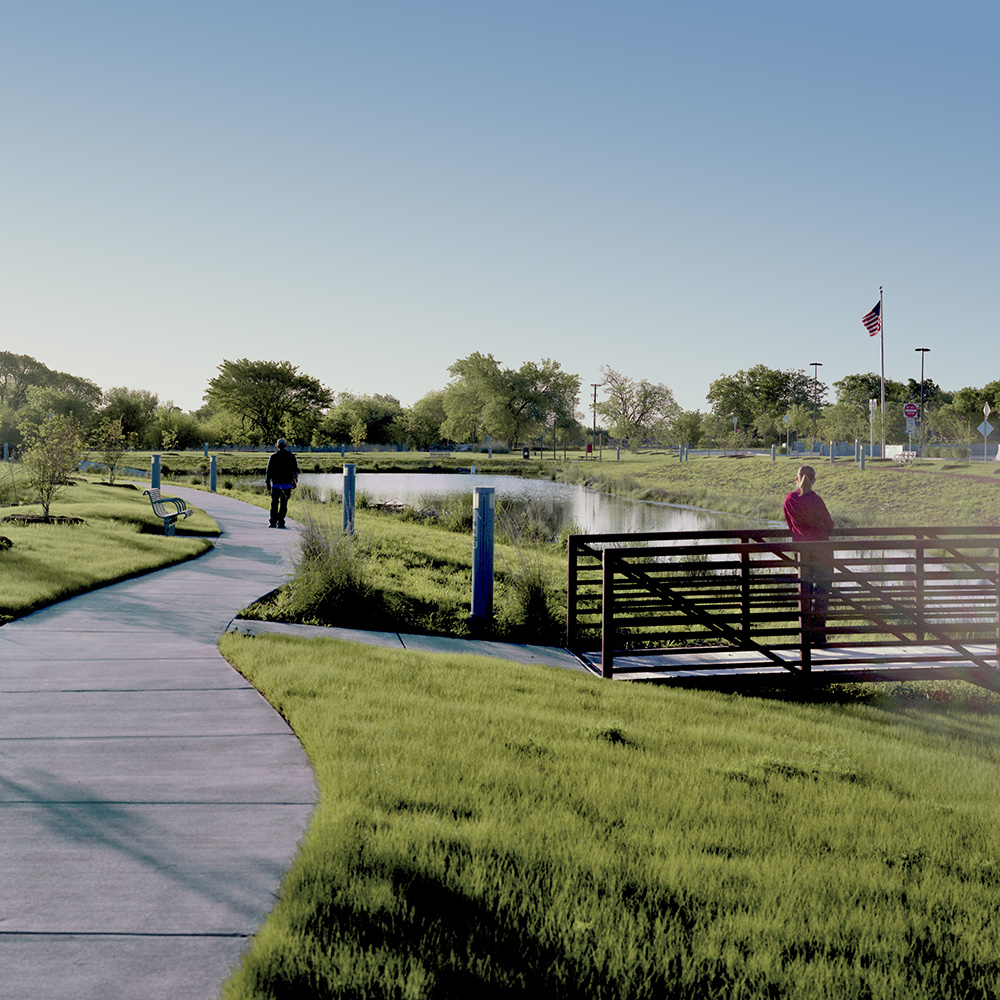 A bike path and bridge next to pond.