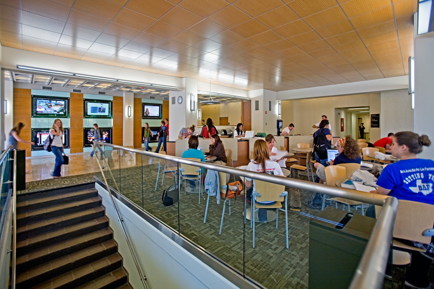 Students working at tables in a college lobby space.