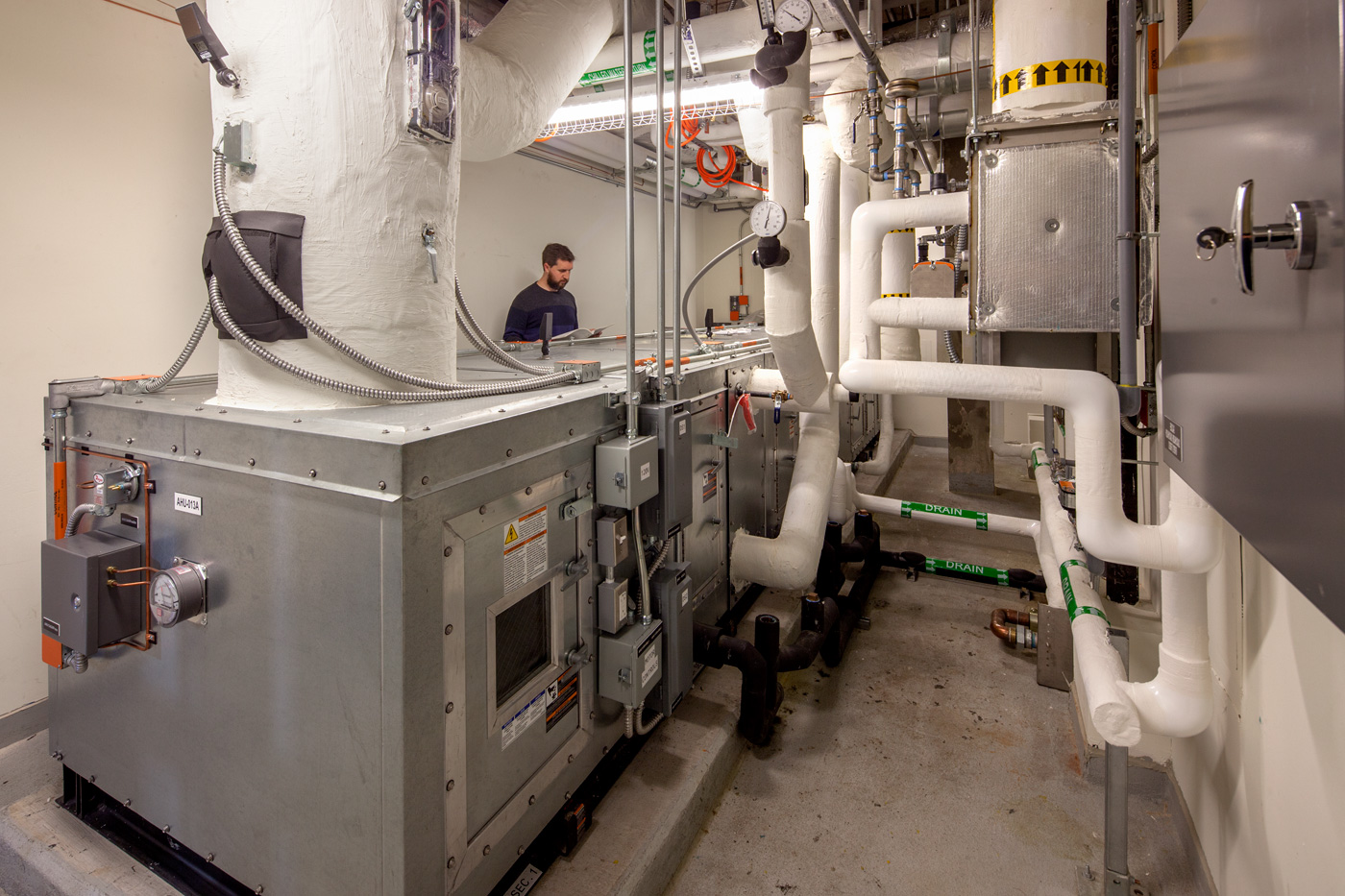 A man in a mechanical room for a large building.