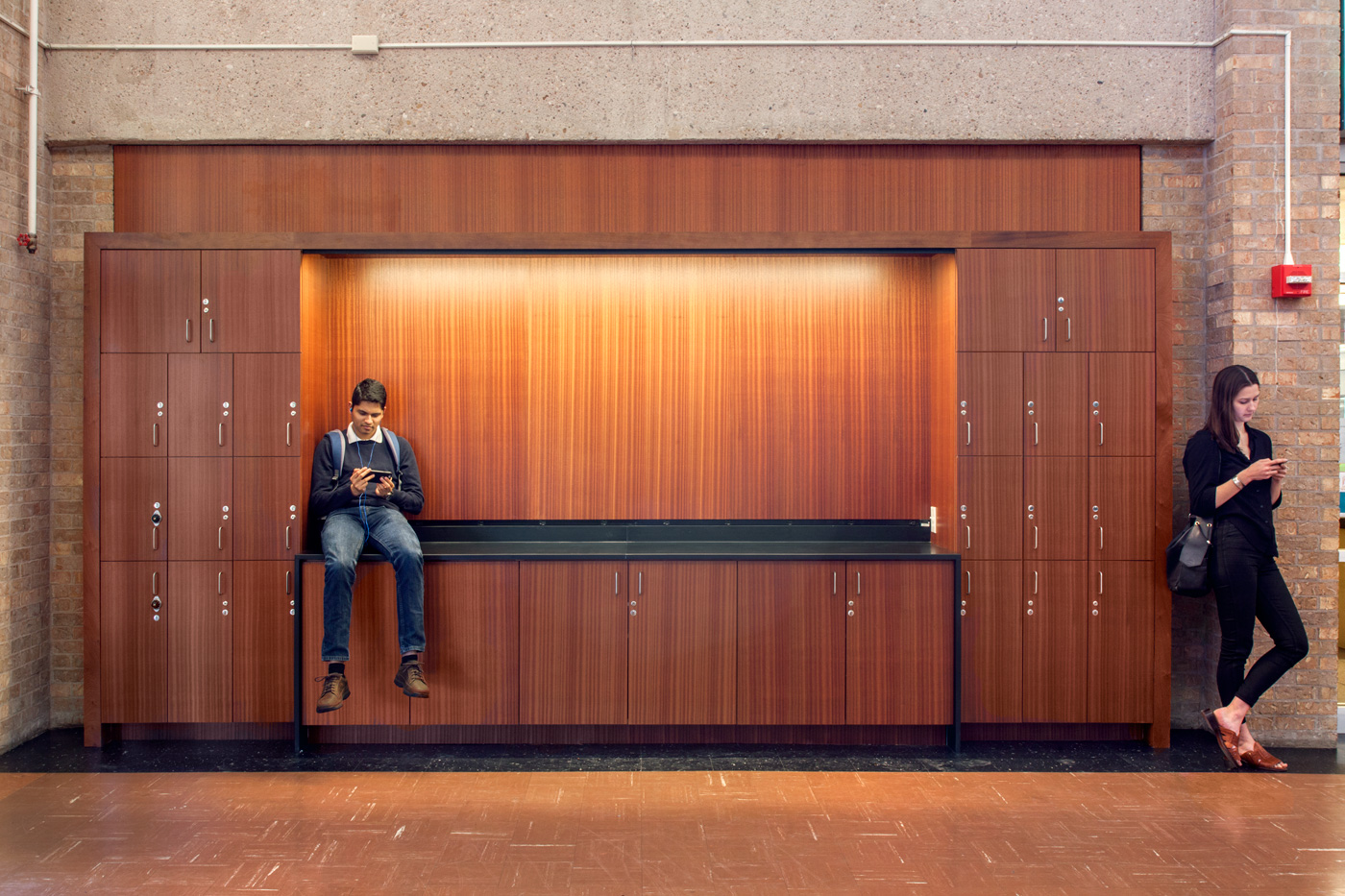 People on their phones near wooden lockers.