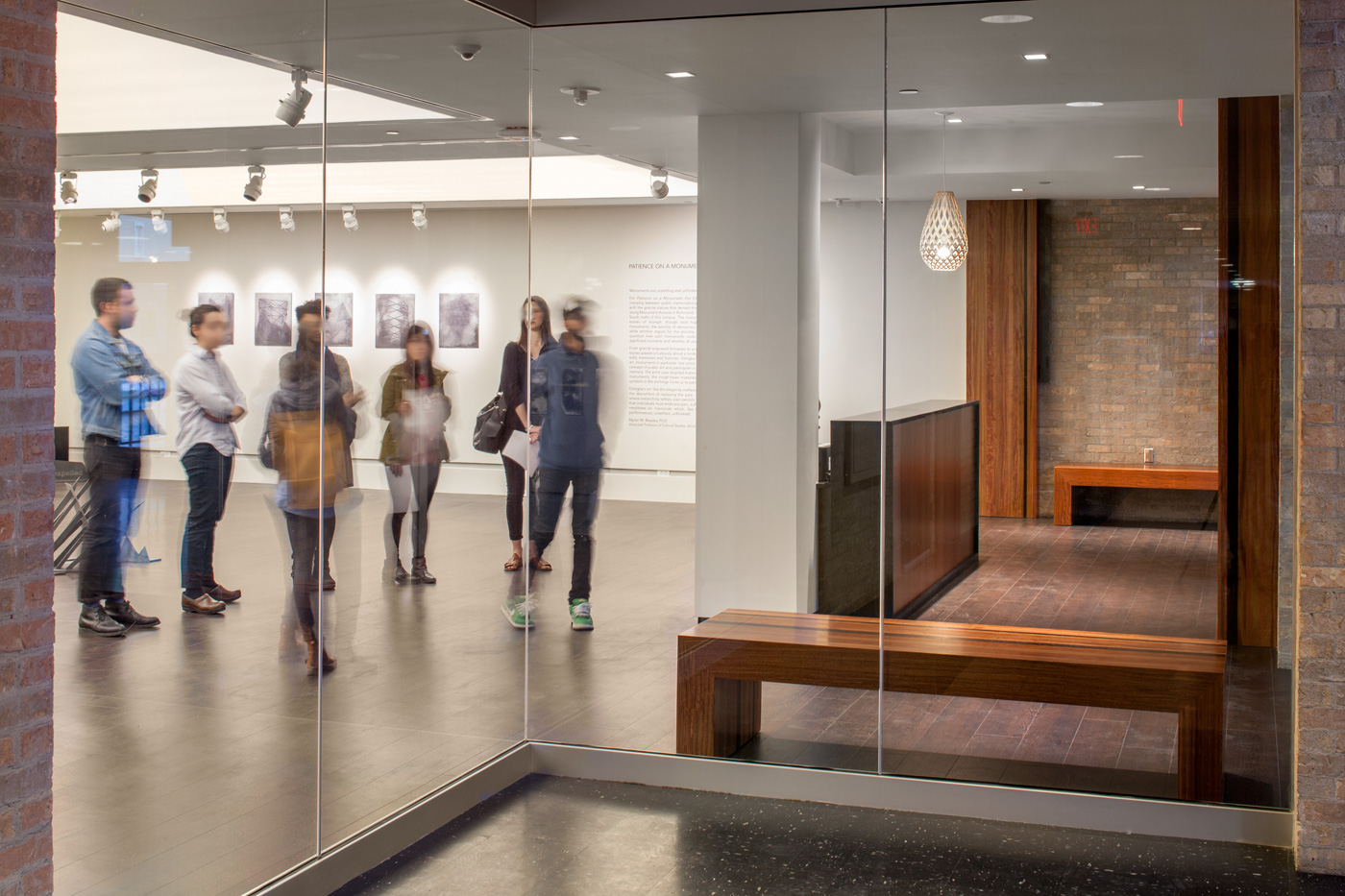 People in art exhibit visible through large glass wall.