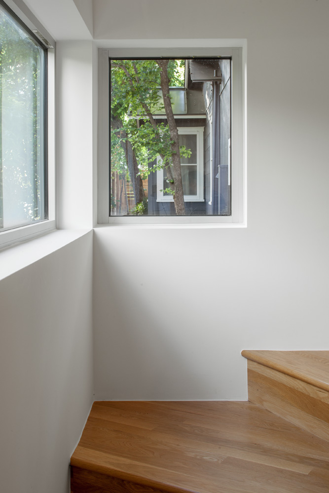 Two windows in a corner next to stairs.