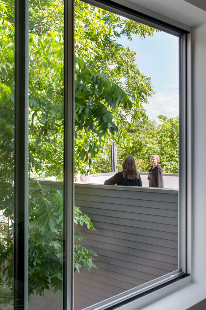 People talking on a second-floor roof deck.