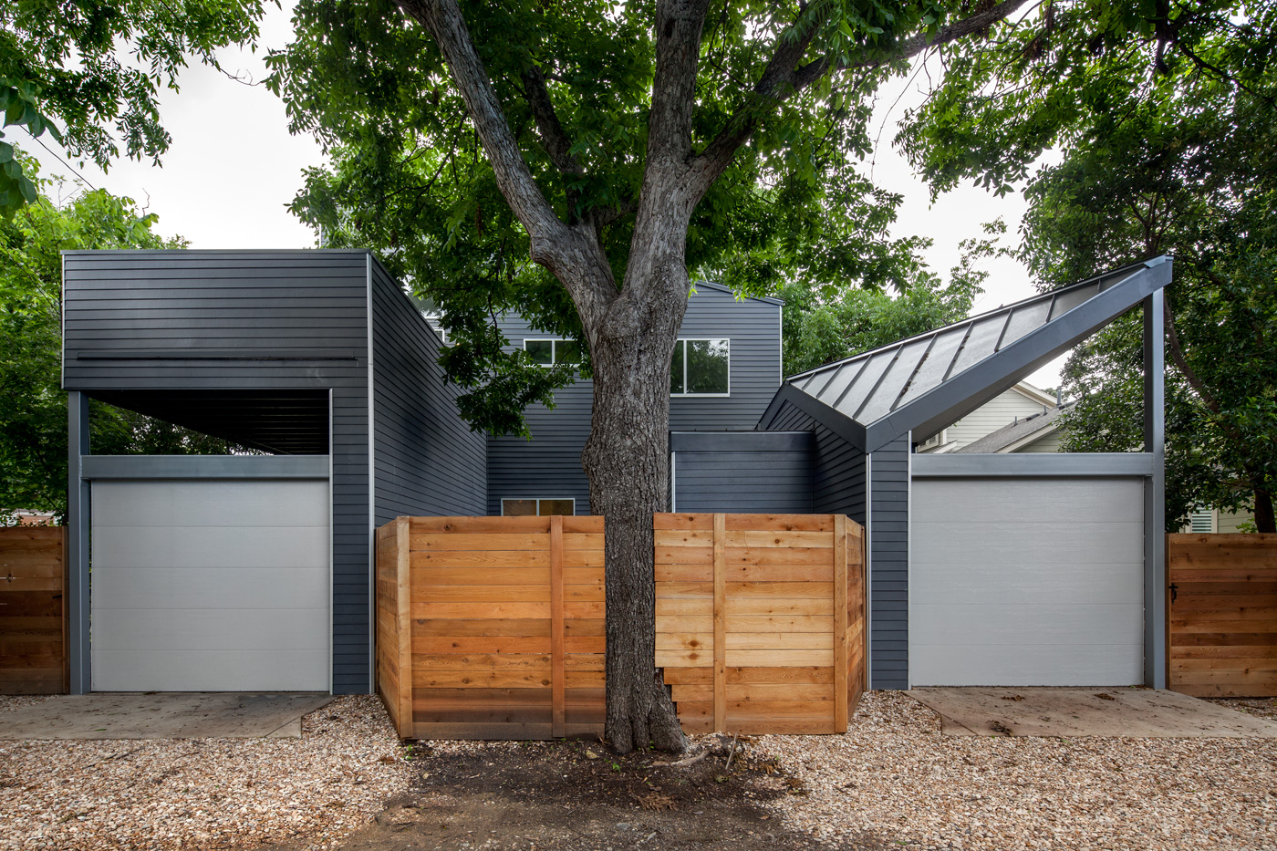 Two garages split evenly by a fence and a tree.