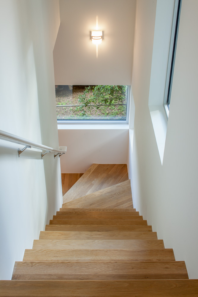 A wooden stair set that cut through white walls.