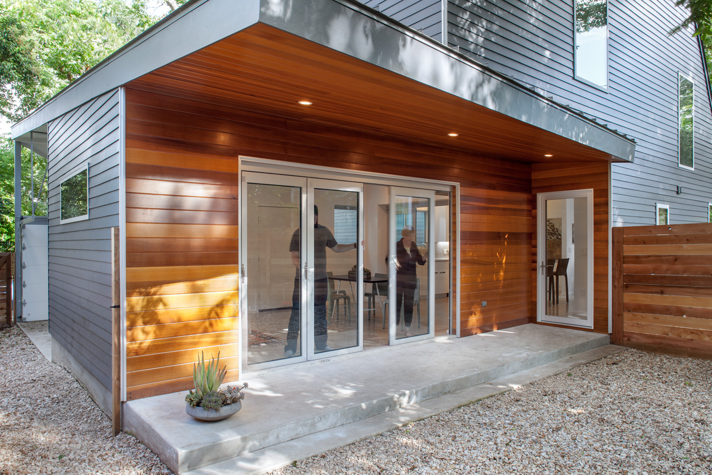 People moving glass sliding doors into a large opening of a house.