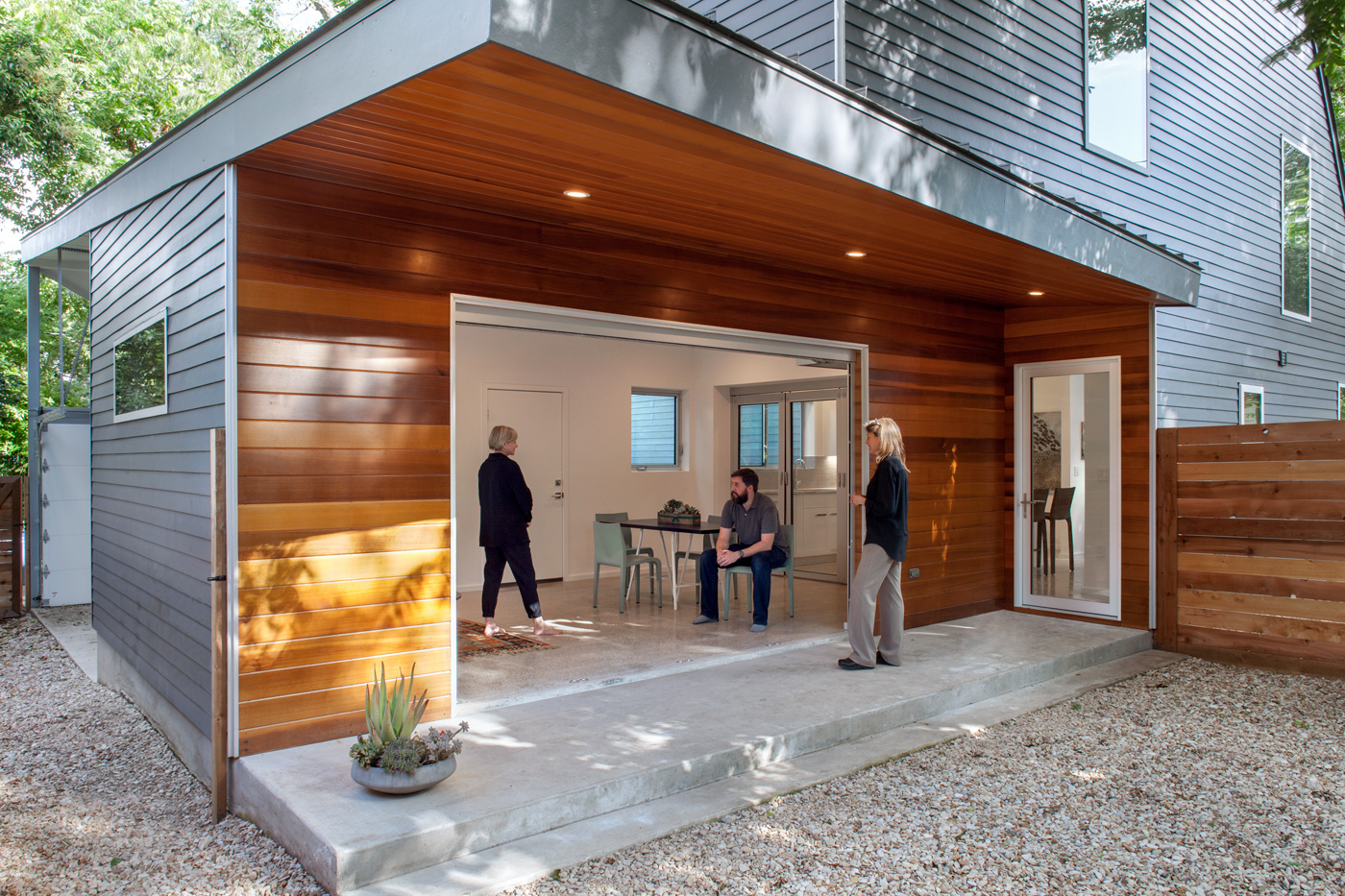 A living and dining room open to a back yard through large opening.