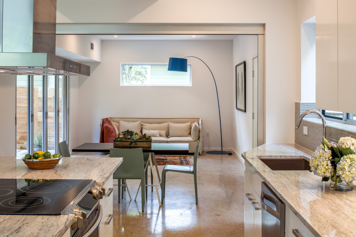 A small dining table in between a kitchen and a living room.