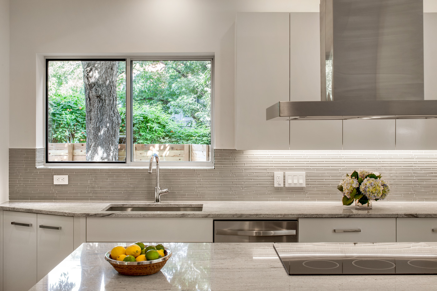 A sink in front of a window in a white kitchen.