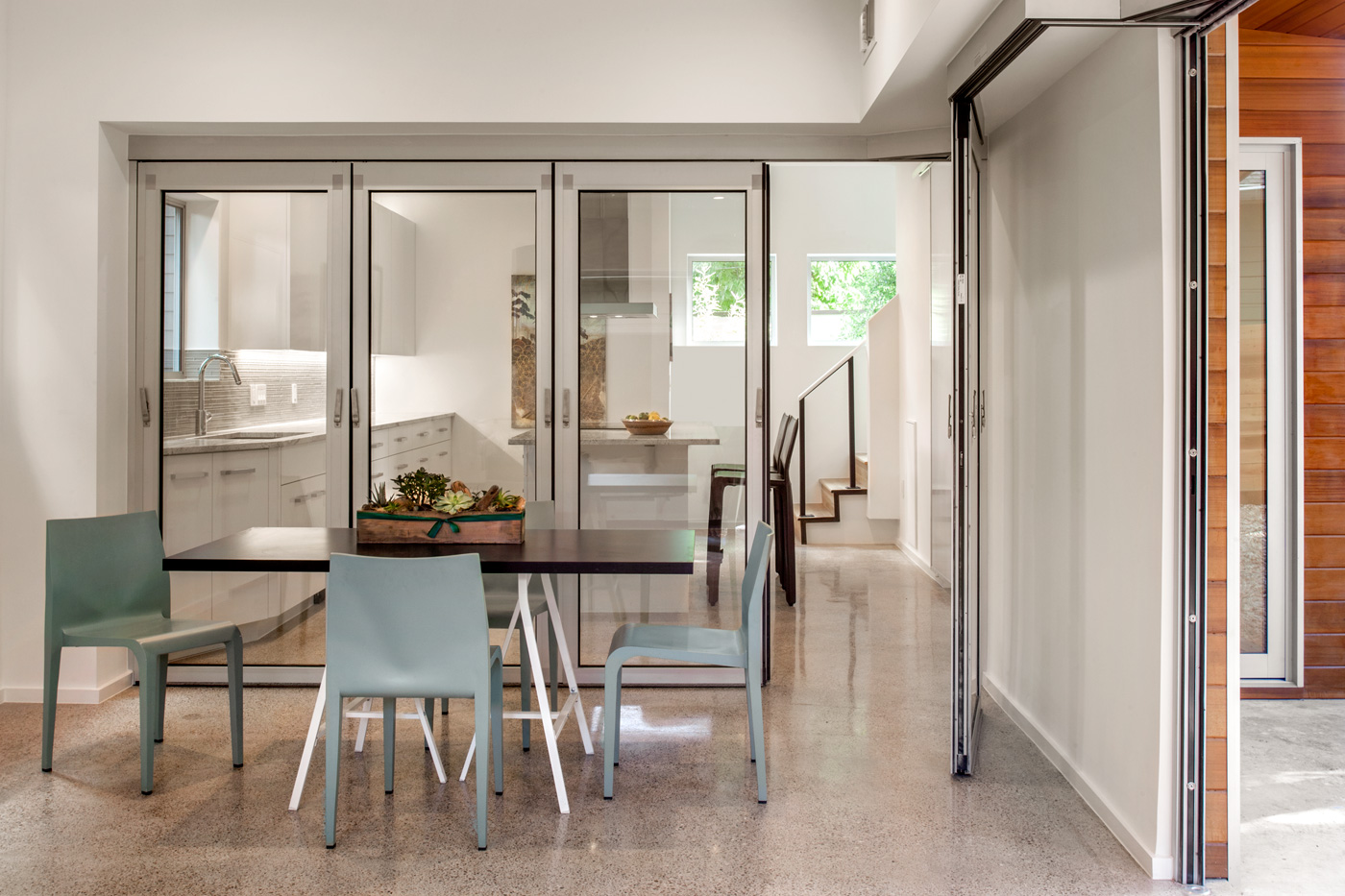 Glass sliding doors between a kitchen and a dining room.