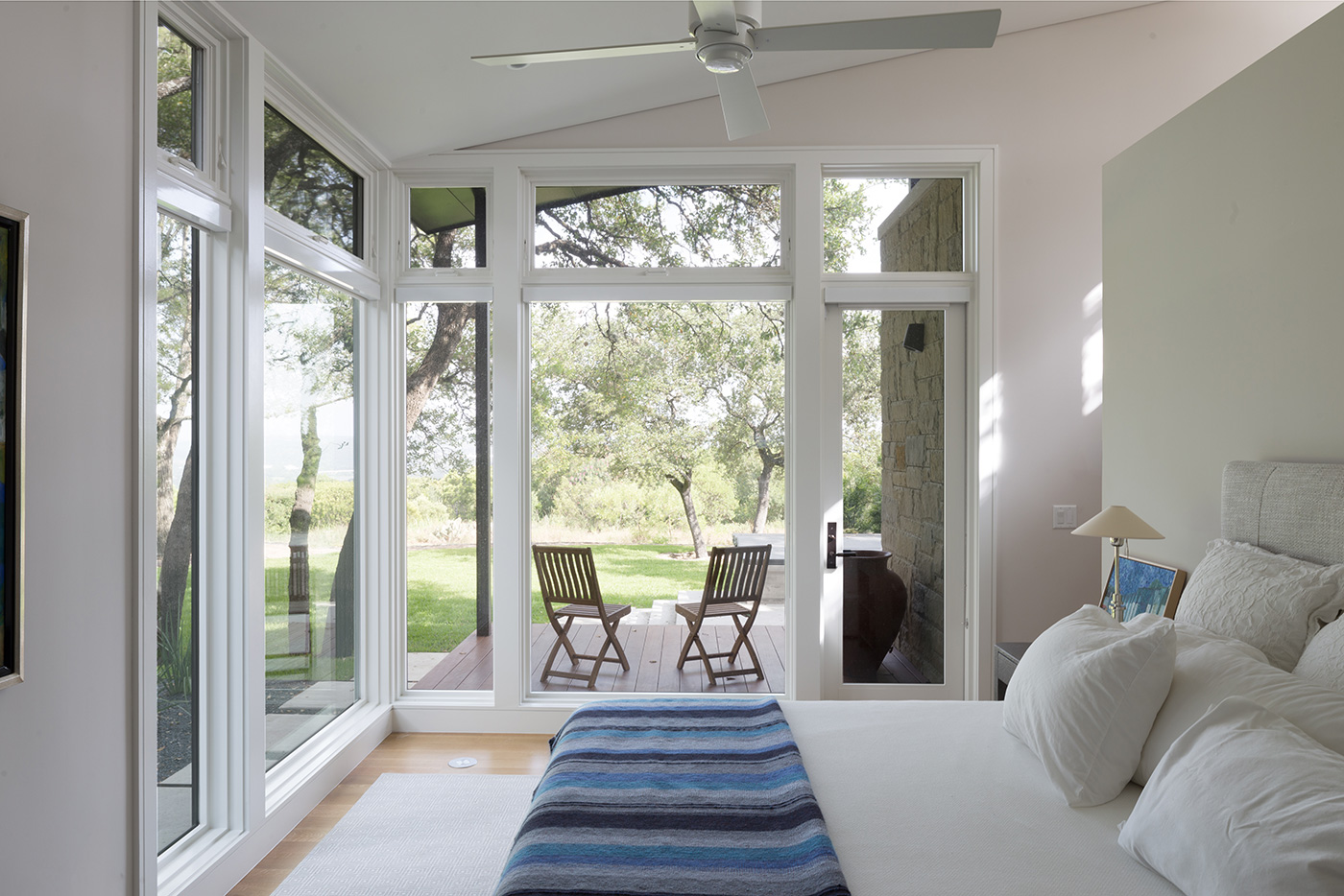 A bedroom with large windows that look out to a back yard.