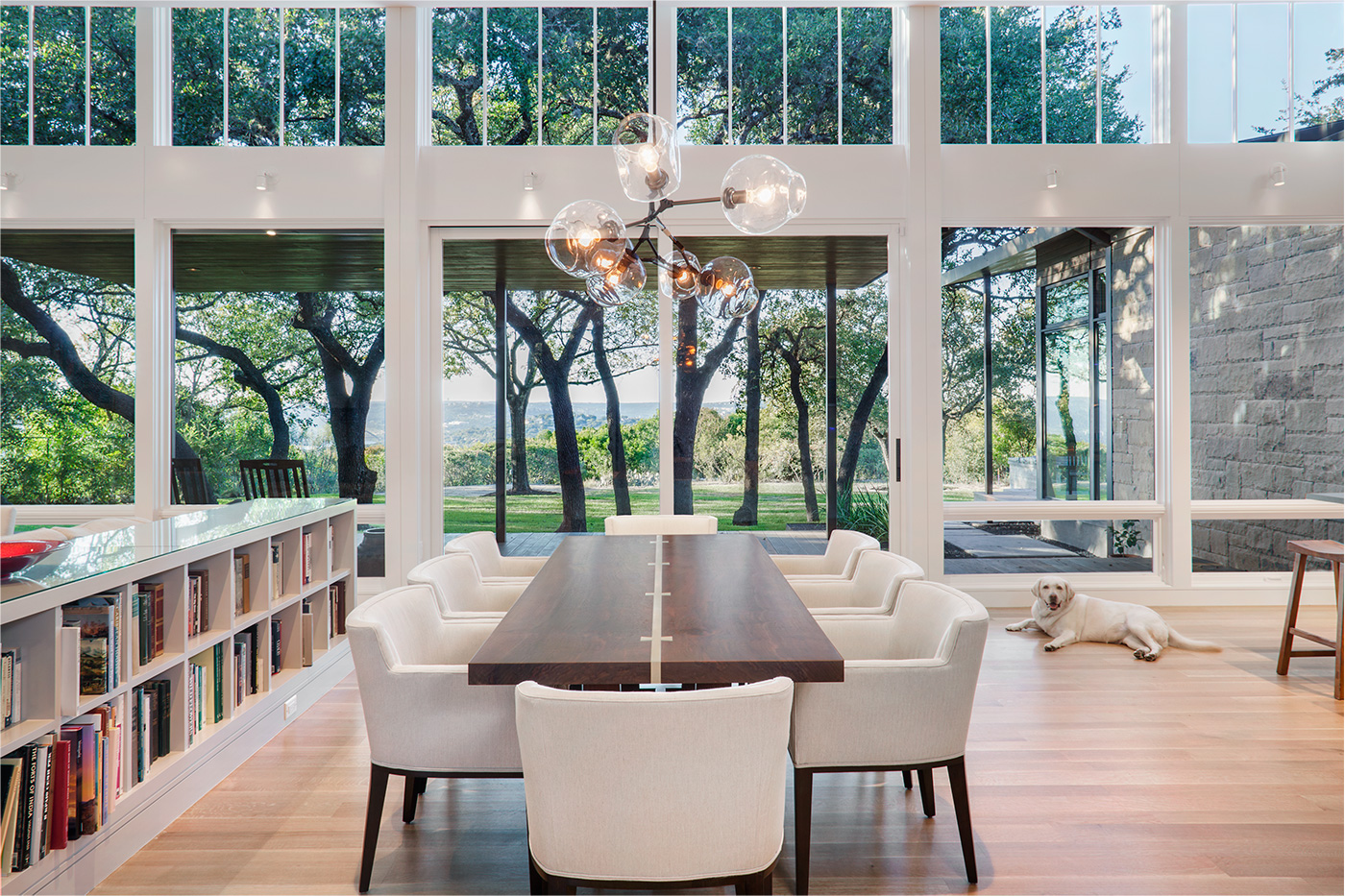 a central dining table Infront of large windows that look out to a view.
