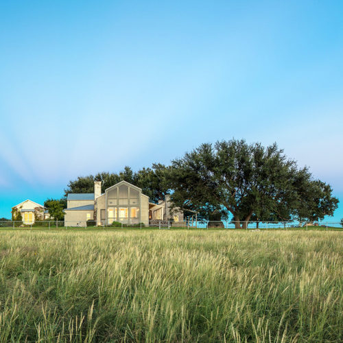 A ranch house visible from its tall grass property.