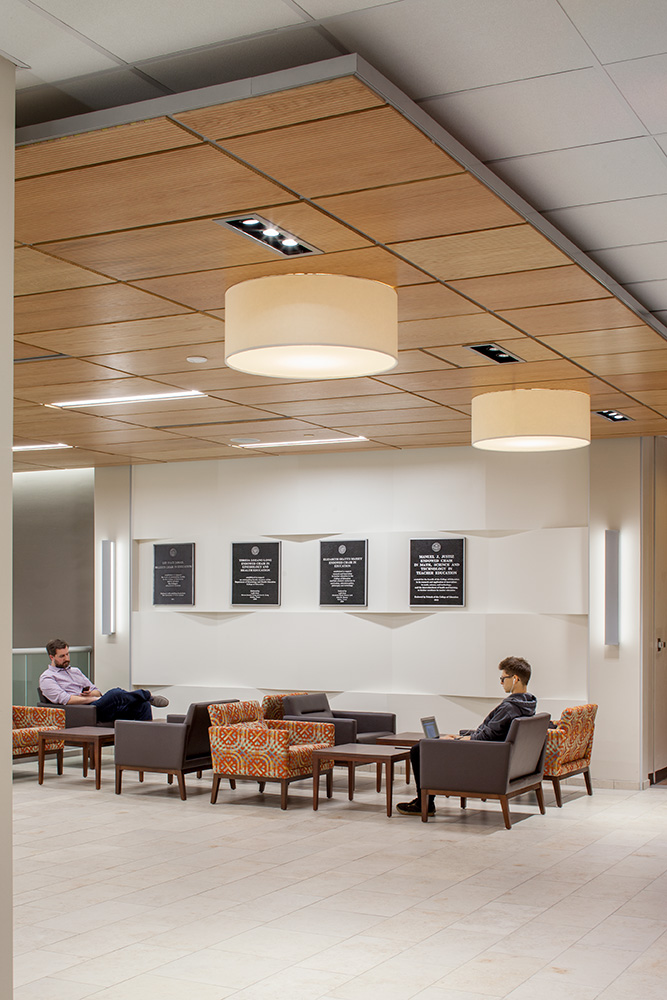 Two people working at a seating area. with plaques on the wall behind them.