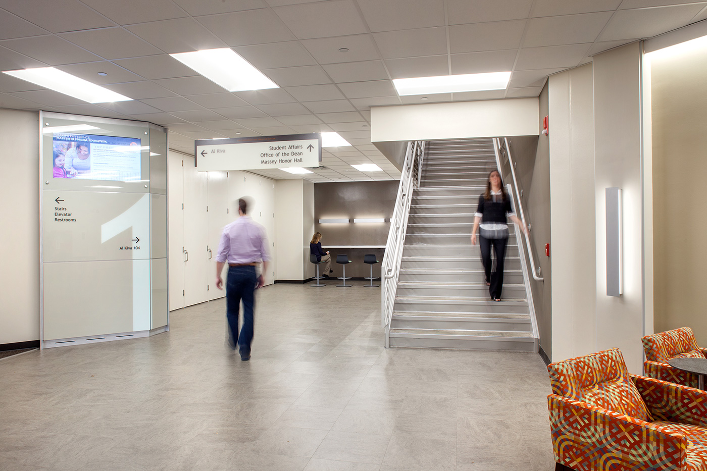 Women walking down a set of stairs to a bright open hallway.
