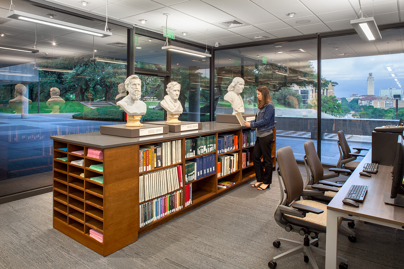 A woman researching at a standup desk in a library.