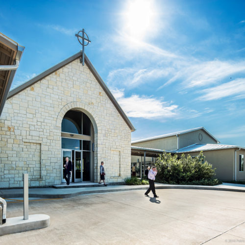 People leaving a church into its parking lot.