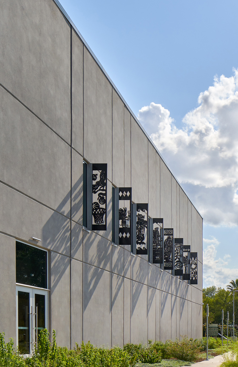 Concrete wall of building with detailed metal sheets ejecting out to cast shadows back on the wall.