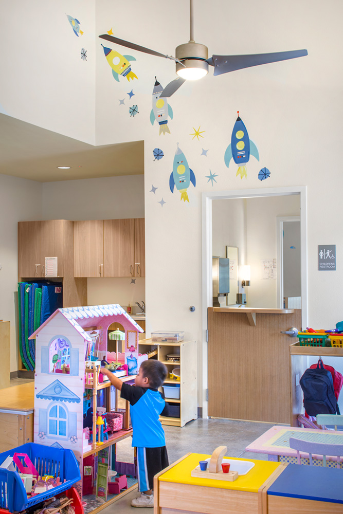 Child playing with toys inside playroom inside a building.