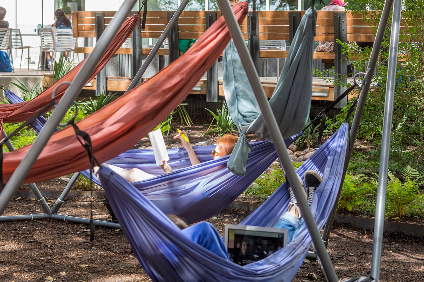 People relaxing in hammocks connected to a metal structure.