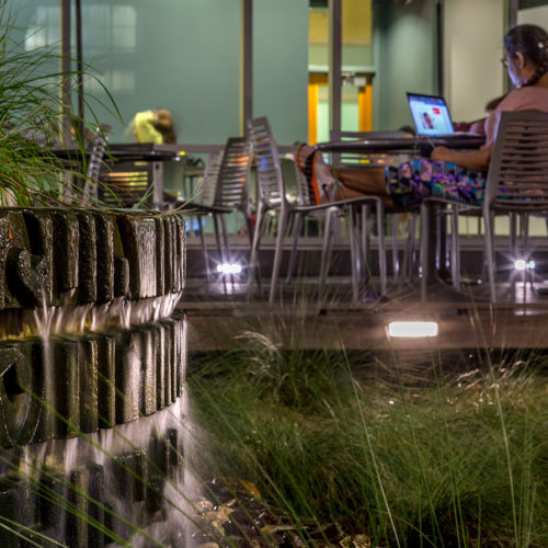 A small water feature Infront of an outdoor seating area.