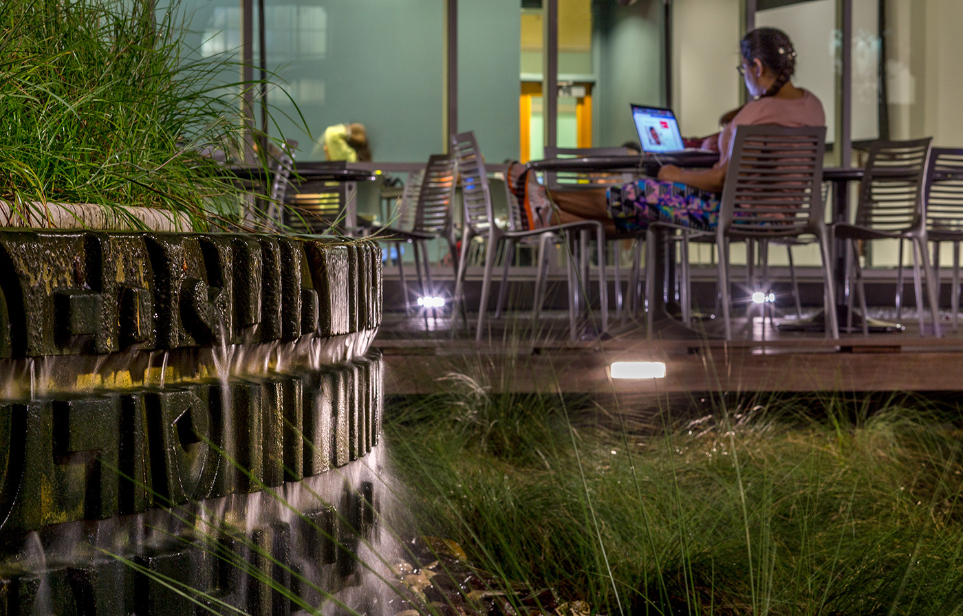 A small water feature Infront of an outdoor seating area.