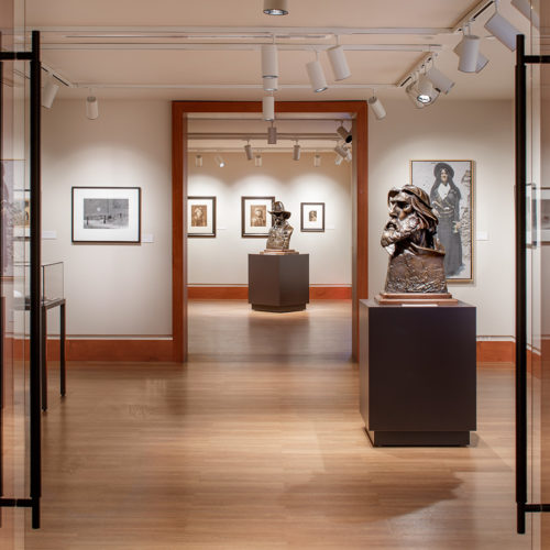 Wood colored bight exhibit rooms with two bronze busts.