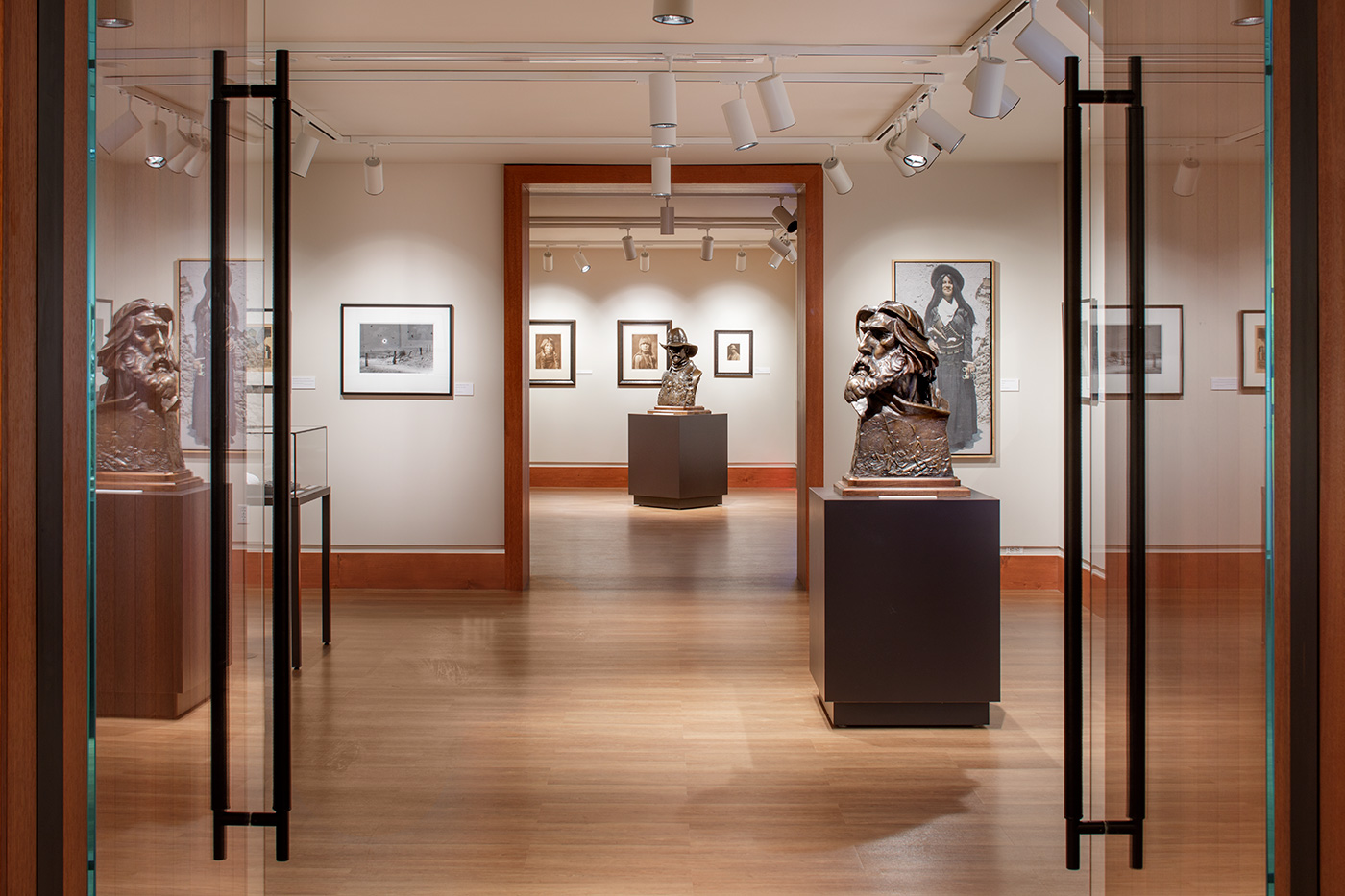 Wood colored bight exhibit rooms with two bronze busts.